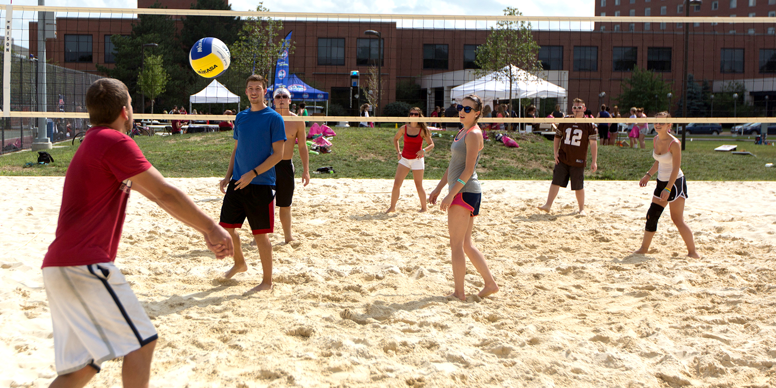 Students play sand volleyball.